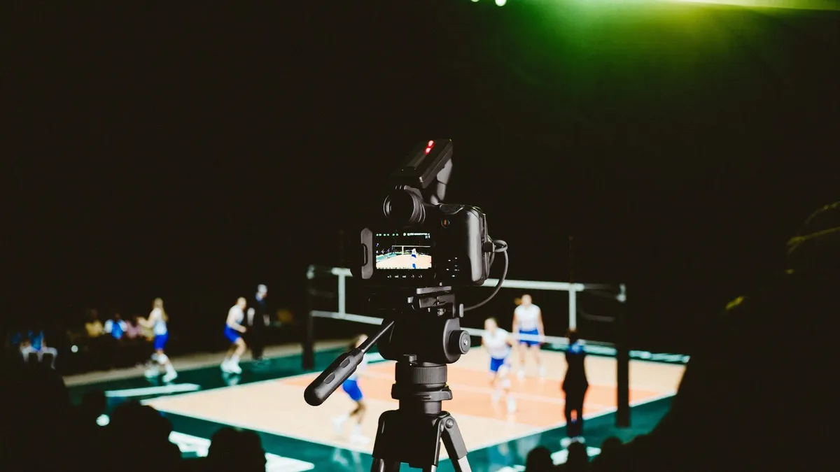 Una telecamera riprende una partita di pallavolo dal bordo campo